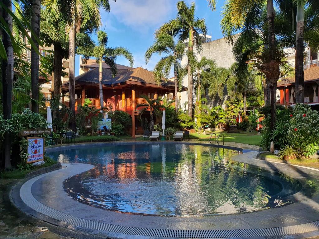 einen Pool vor einem Haus mit Palmen in der Unterkunft Boracay Tropics Resort Hotel in Boracay