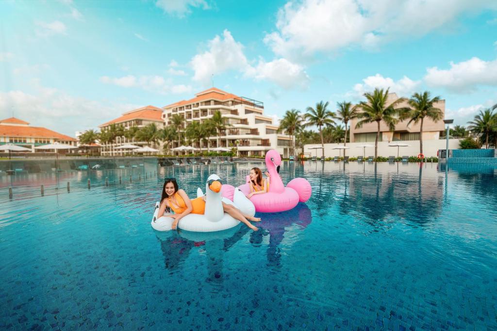 three women riding on inflatables in the water at a resort at Pullman Danang Beach Resort in Da Nang