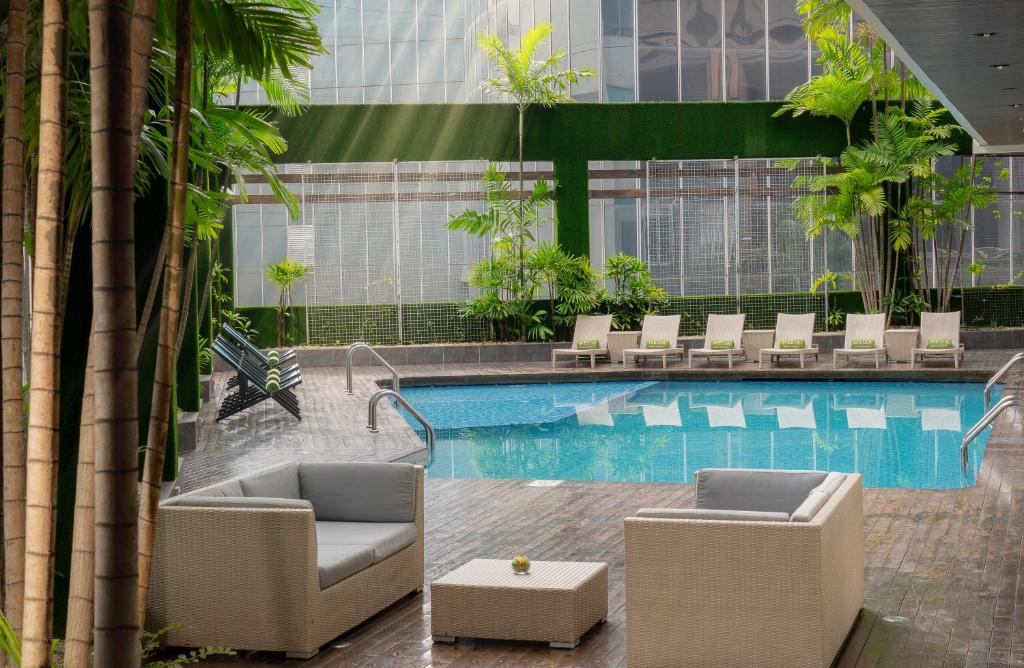 a hotel swimming pool with chairs and a table at Meli&aacute; Kuala Lumpur in Kuala Lumpur