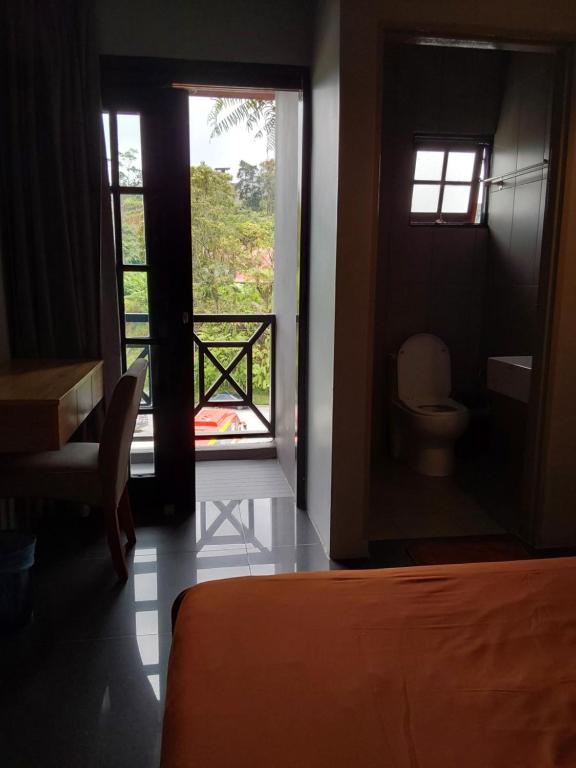 a room with a bed and a bathroom with a window at BRICKS Cameron Hostel in Tanah Rata