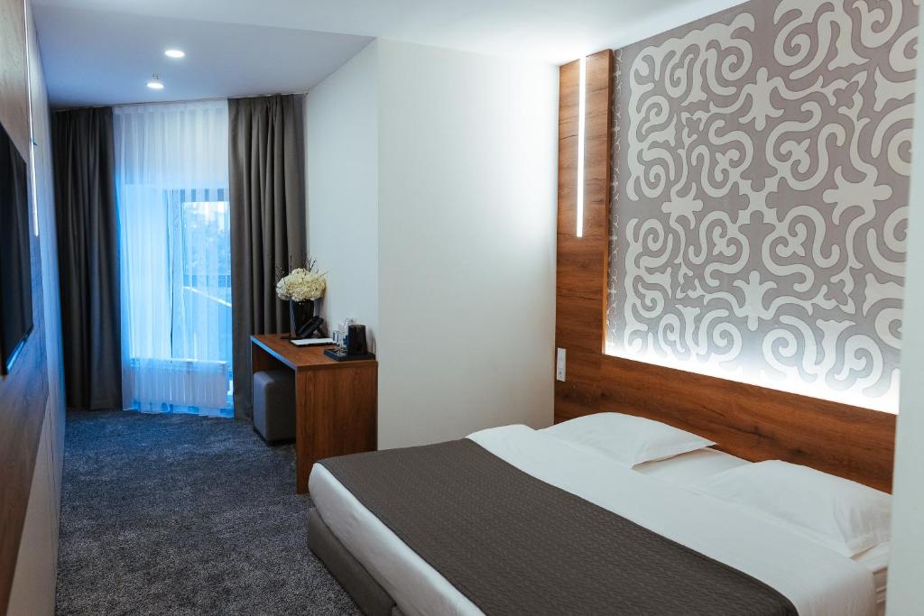 ein Hotelzimmer mit einem Bett und einer Wand in der Unterkunft DUO Futuro Hotel Bishkek in Bischkek
