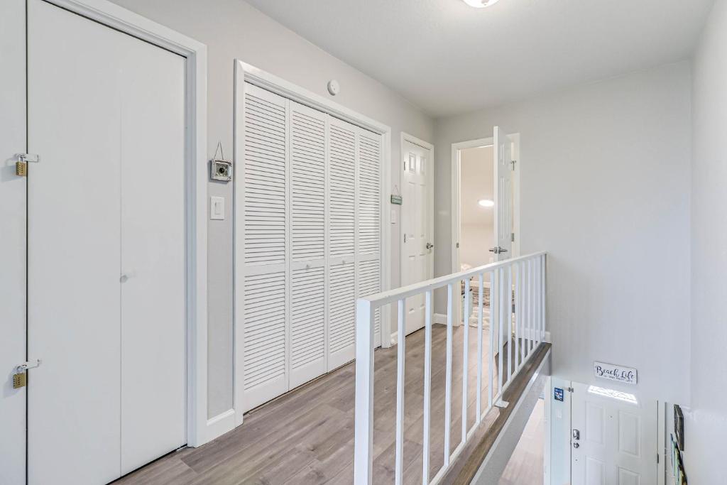 a hallway with white walls and a staircase with a window at Bayfront Kontiki in Rockport