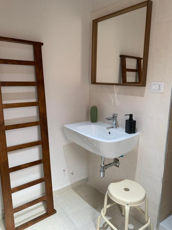 een badkamer met een wastafel, een spiegel en een kruk bij Il Verdi home in Caserta
