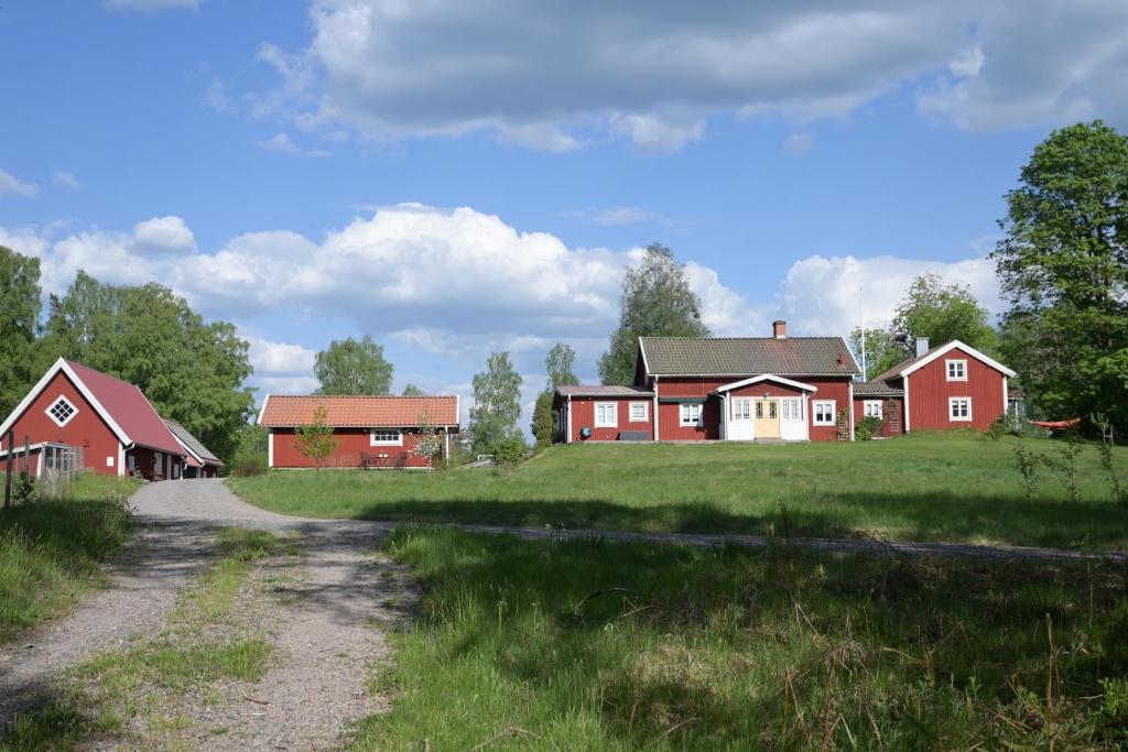 un grupo de casas rojas en un campo con un camino de tierra en Smålandstorpet en Hok