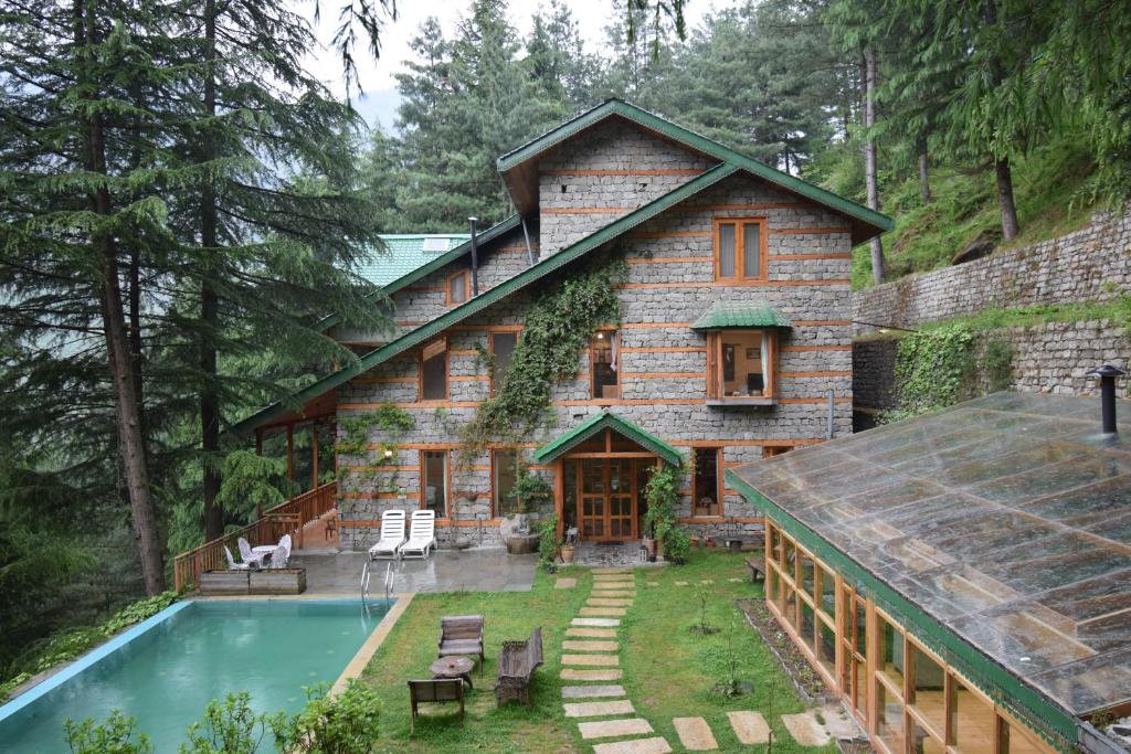 a house with a swimming pool in front of it at Kudrat - A Boutique Homestay- Tirthan Valley in Banjār