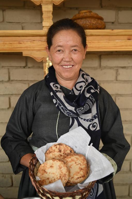 a woman is holding a basket of food at Stone Hedge Hotel in Nubra