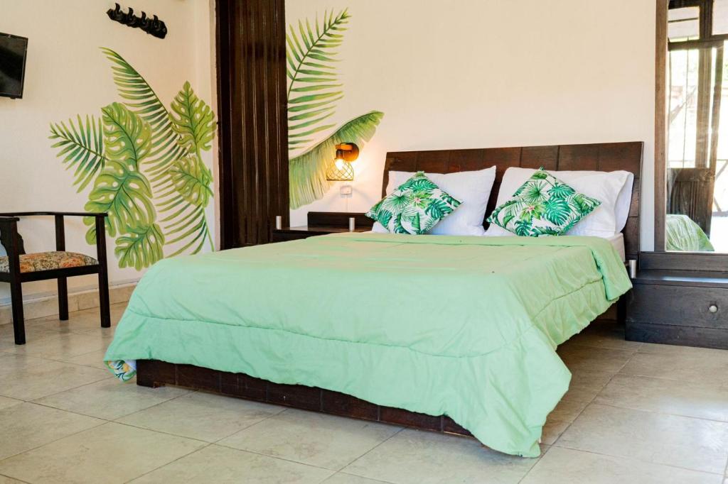una camera da letto con un grande letto e un piumone verde di Playa Alta Hostal a Santa Marta