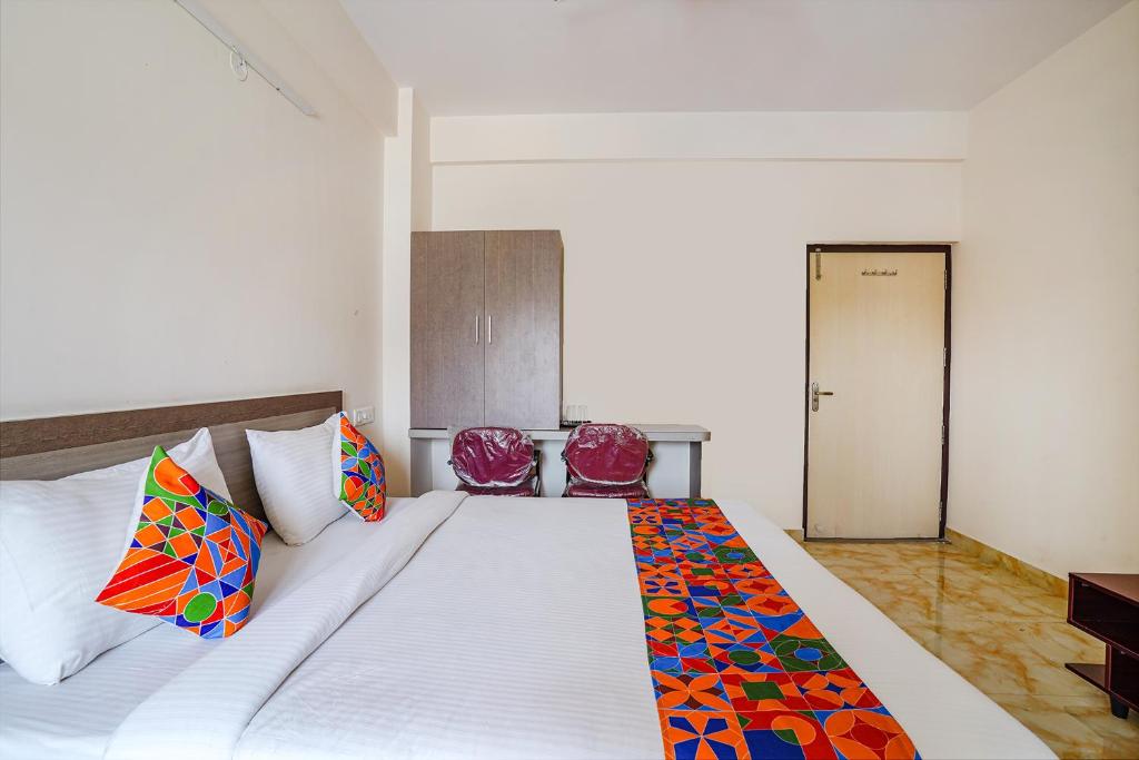ein Schlafzimmer mit einem großen weißen Bett mit bunten Kissen in der Unterkunft FabExpress MS Comforts in Bangalore