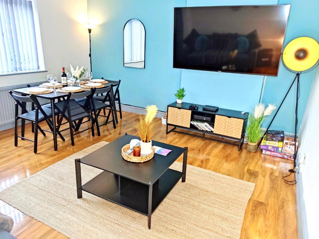 a living room with a tv on a blue wall at 3-Bedroom Leeds Beach Home - 8 minutes to City Centre, Free Private Parking for 2 Cars, 70" Smart TV, Projectors in Bedrooms, Free WiFi - Ideal for Family and Contractors in Killingbeck