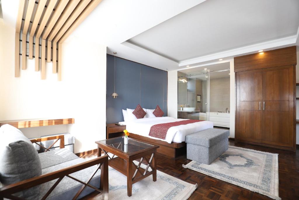 Apex Business Hotel في كاتماندو: غرفه فندقيه بسرير واريكه