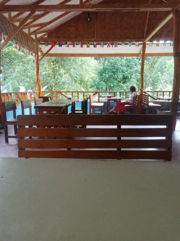 a wooden bench in a pavilion with a person sitting at a table at Orchid Bugalows. in Timbanglawang