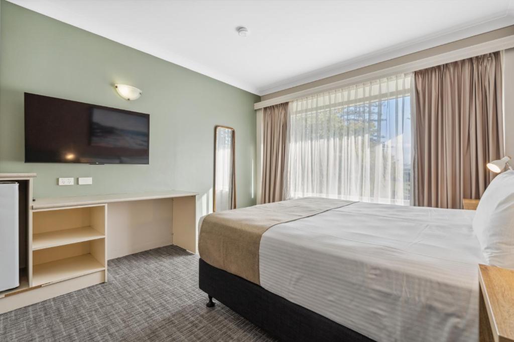 a hotel room with a bed and a flat screen tv at Glenelg Dockside Motel in Adelaide