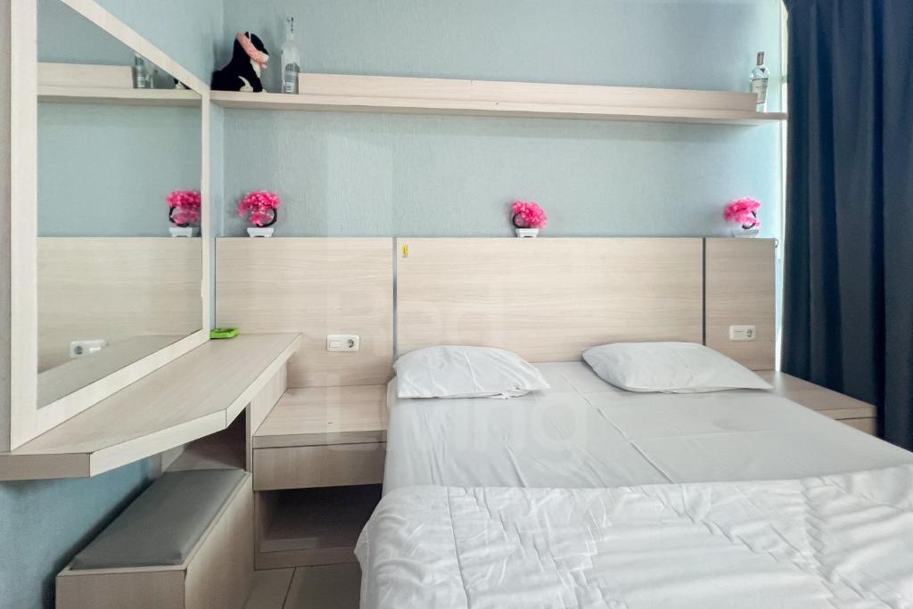 ein Schlafzimmer mit einem Bett und einem Schreibtisch mit rosa Blumen in der Unterkunft RedLiving Apartemen Treepark City - Nuansa Property Tower Alpine in Kebonnanas