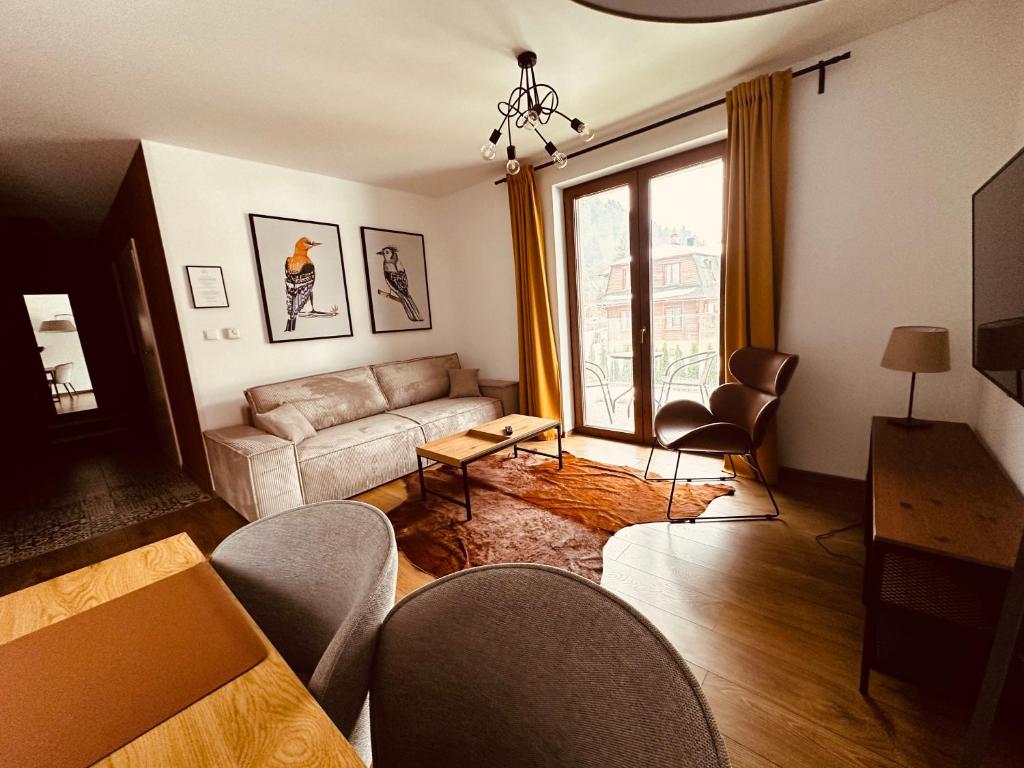 sala de estar con sofá, sillas y ventana en Villa Monica Apartamenty, en Szczyrk