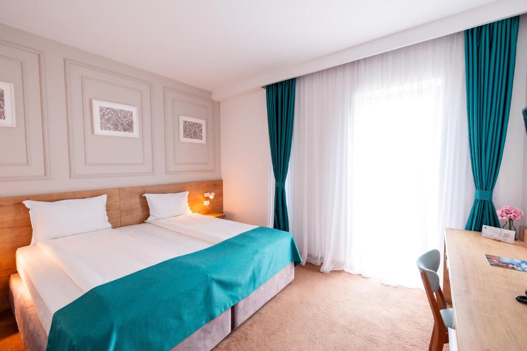 1 dormitorio con 1 cama con cortinas azules y ventana en Stil Hotel en Bucarest