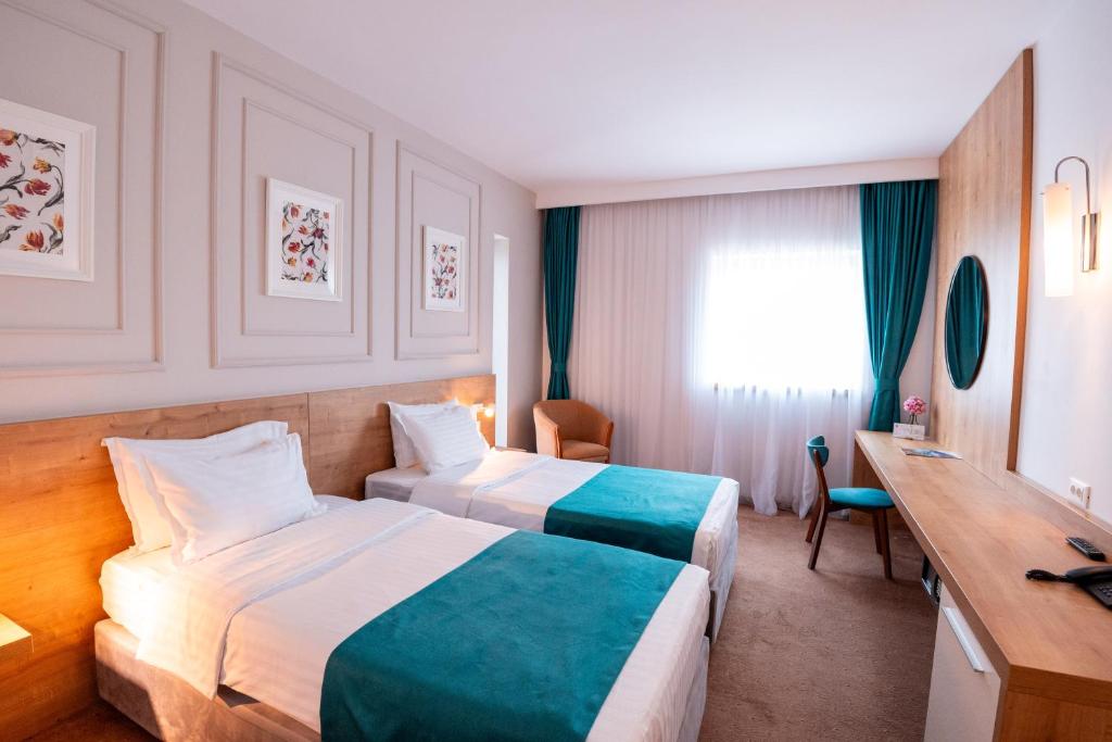a hotel room with two beds and a desk at Stil Hotel in Bucharest