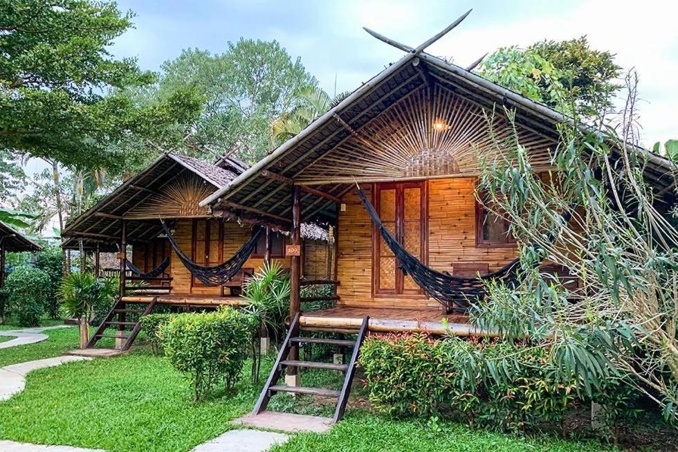 ein Holzhaus mit einer Hängematte davor in der Unterkunft Pai Country Hut in Pai