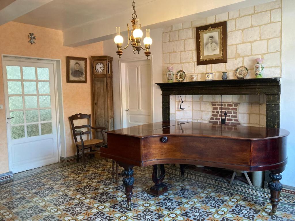 een kamer met een piano voor een open haard bij La Grange aux Tommies - Pays du Coquelicot in Bus Les Artois