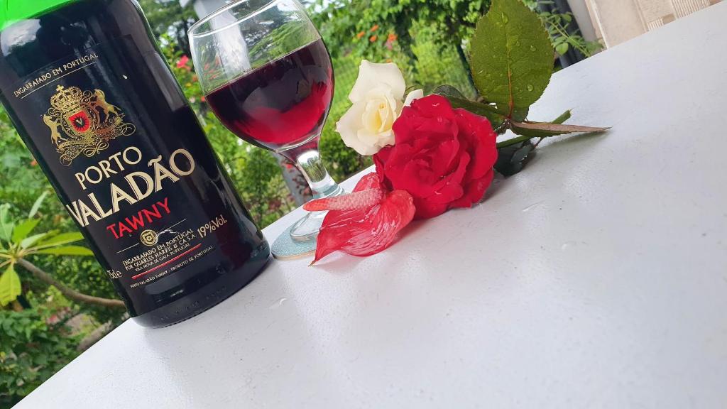 a bottle of wine and a glass of wine and a rose at Jardin Fleuri de Lety in Nosy Be