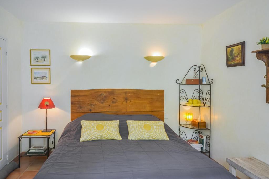 sypialnia z dużym łóżkiem z drewnianym zagłówkiem w obiekcie Chambres d'hôtes "Le Colombier" w mieście Venasque