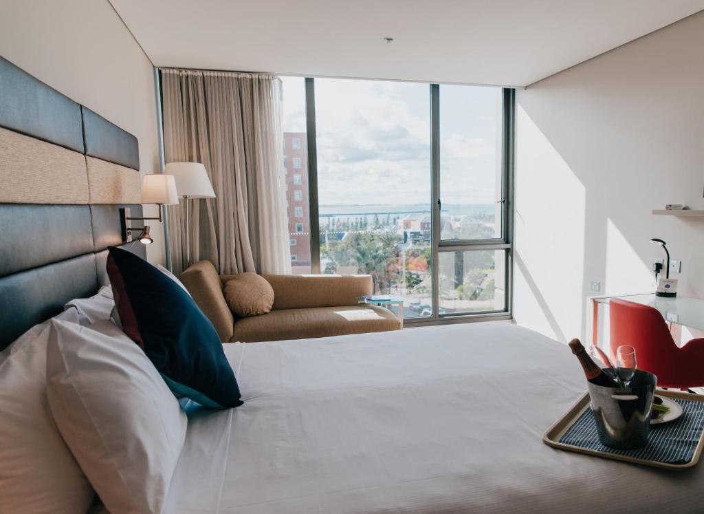 una camera d'albergo con letto, divano e finestre di Novotel Newcastle Beach a Newcastle