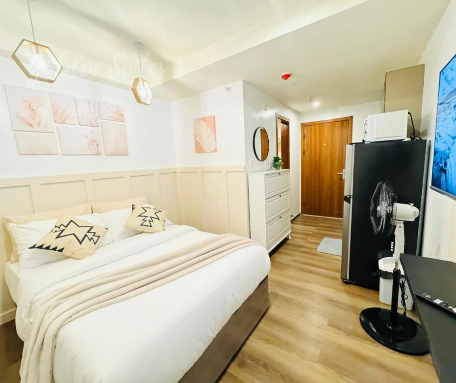 a white bedroom with a bed and a desk at GOLDEN SUITES BAGUIO in Baguio
