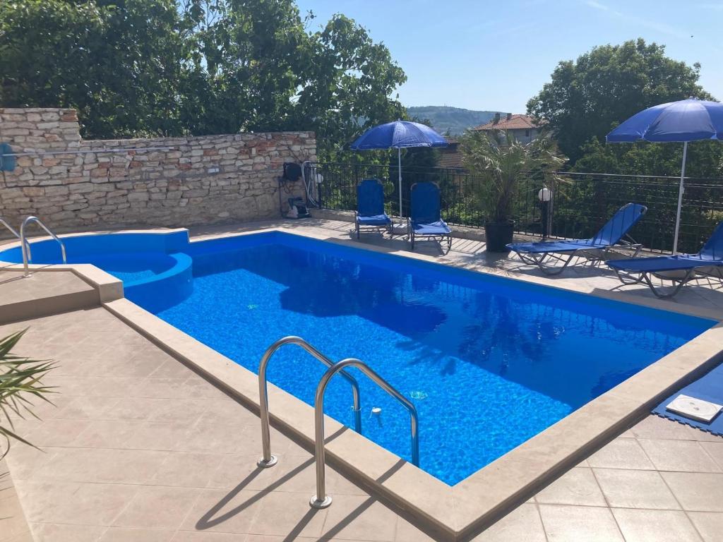 a blue swimming pool with blue chairs and umbrellas at Panorama Pearl in Balchik
