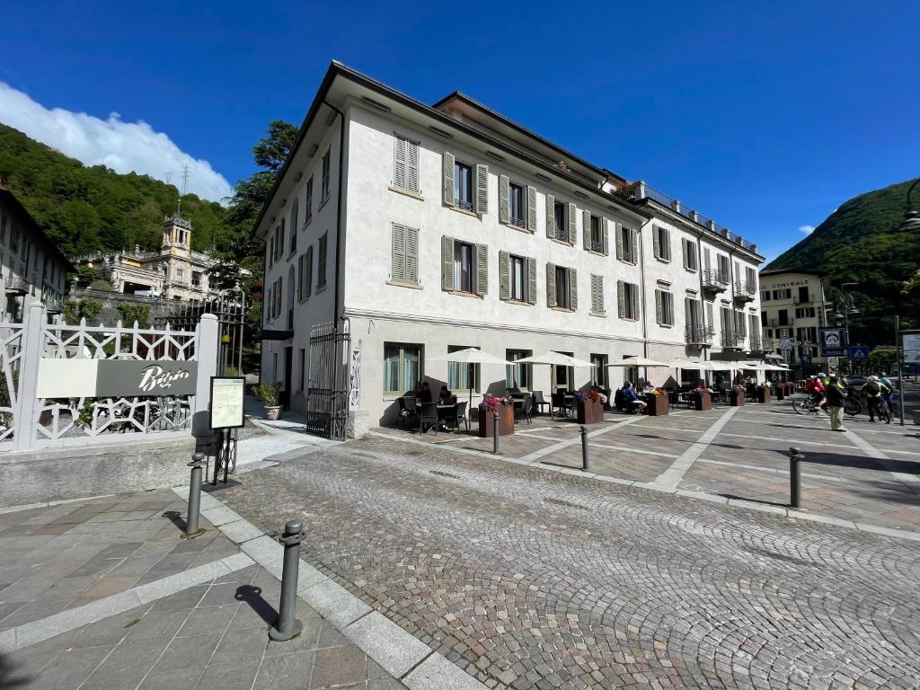 a large white building on a cobblestone street at Hotel Bigio in San Pellegrino Terme