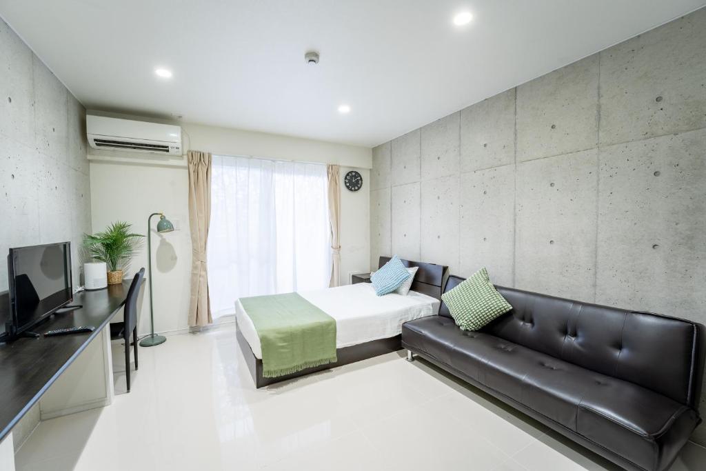 1 dormitorio con cama, sofá y TV en Hotel Paradiso Miyakojima, en Isla Miyako