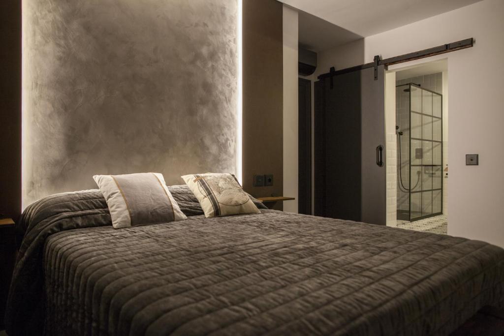 ein Schlafzimmer mit einem Bett mit einer grauen Bettdecke in der Unterkunft La Aduana The Lodging Experience in Astorga