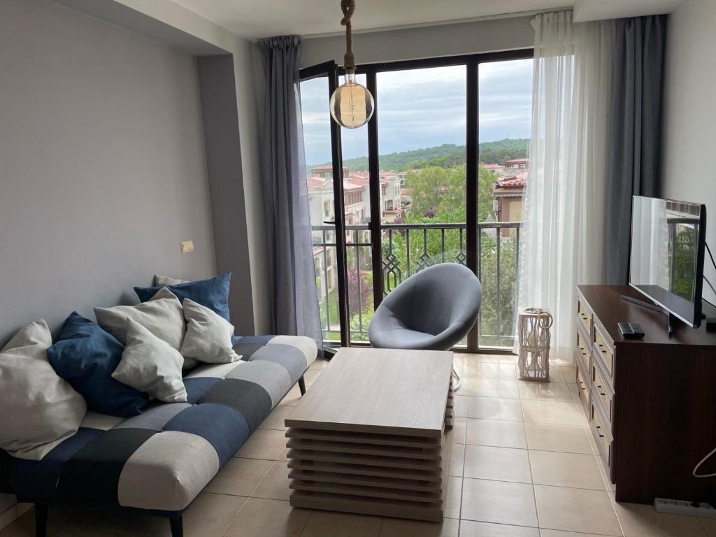 uma sala de estar com um sofá azul e uma varanda em Green Life Beach Resort Sozopol Two Bedroom Apartment em Sozopol
