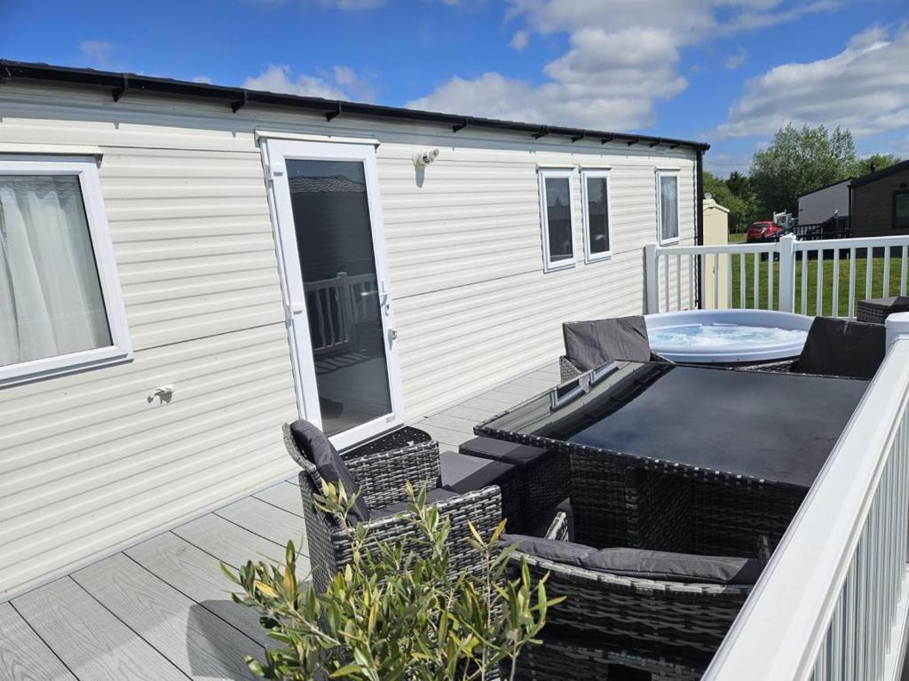 a deck with a table and chairs on a trailer at Luxury Caravan 3 Bedroom 8 Berth With Hot-tub in Lincoln