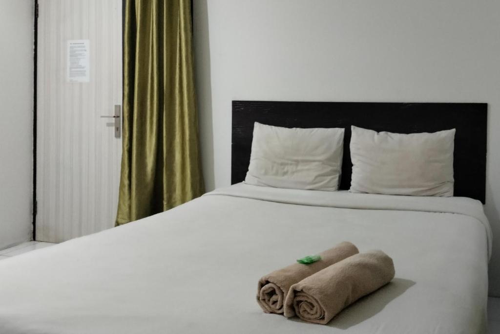 een bed met twee handdoeken bovenop bij Cozy Home 2 RedPartner in Manado