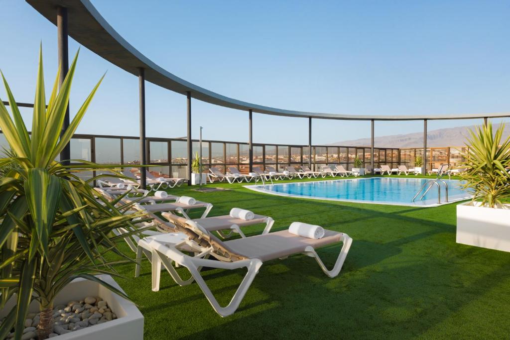a resort with a swimming pool and lounge chairs at Elba Vecindario Aeropuerto Business & Convention Hotel in Vecindario