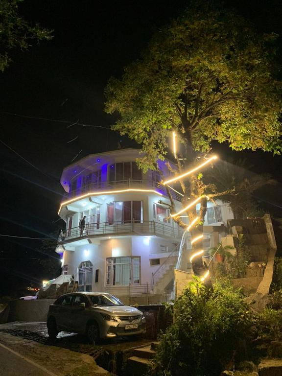 a car parked in front of a large house at night at Hotel Aqua Waterfall in Dharamshala