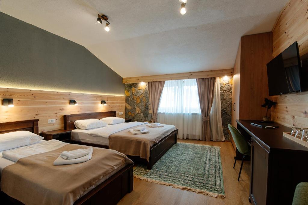 una camera d'albergo con due letti e una televisione di Hotel Zlatni bor a Žabljak