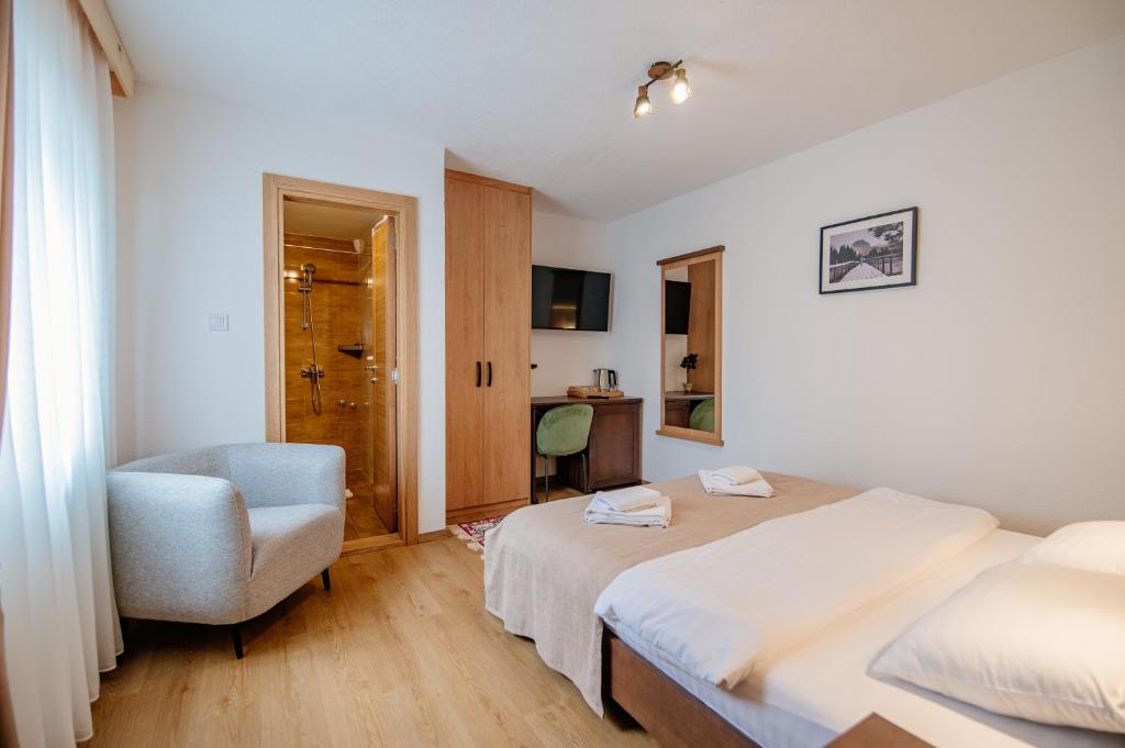 una camera d'albergo con due letti e una sedia di Hotel Zlatni bor a Žabljak