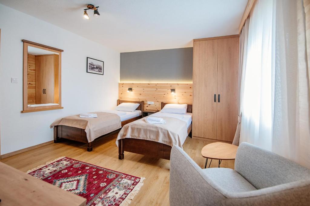 una camera d'albergo con due letti e un divano di Hotel Zlatni bor a Žabljak