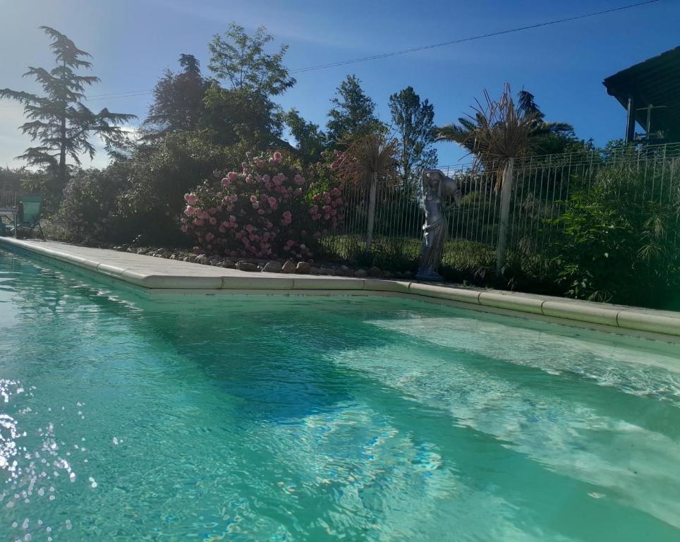 a swimming pool with blue water in front of a fence at Ile des Plaisirs - Domaine de Charme et table d'hôtes Caraïbéenne in Graulhet