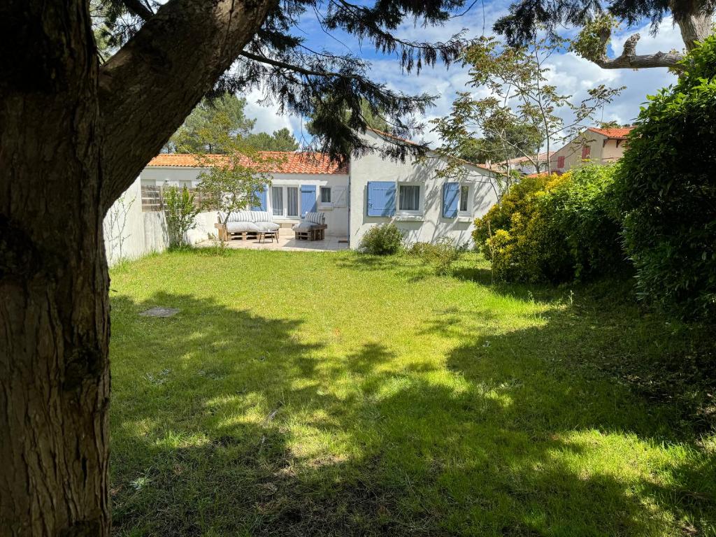 une cour avec une maison blanche et un arbre dans l'établissement Charmante Maison La Tranche sur Mer 100 m de la plage, à La Tranche-sur-Mer