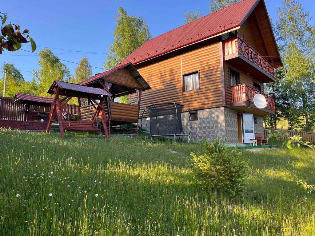 une cabane en rondins avec un toit rouge dans un champ dans l'établissement Сімейний котедж КРАЄВИД, à Mykulychyn