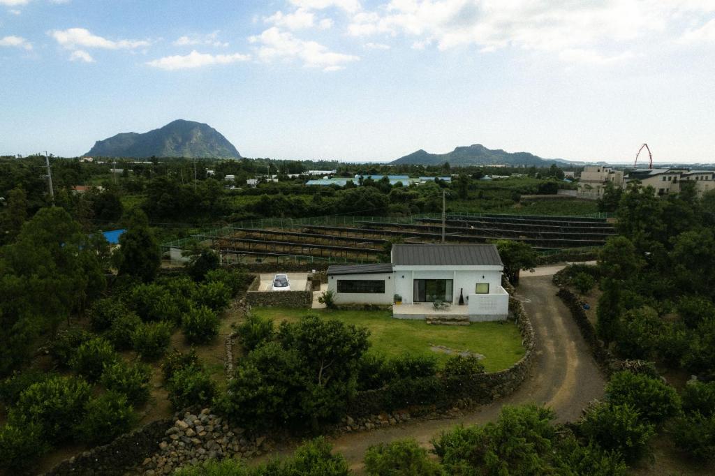 a house in a field with mountains in the background at Dazayo Anseong Gangsaengi House - Pet Friendly in Seogwipo