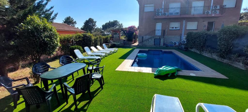 a yard with chairs and a swimming pool with a green turtle at Bravaholidays-602-Lloret Park 2 in Vidreres