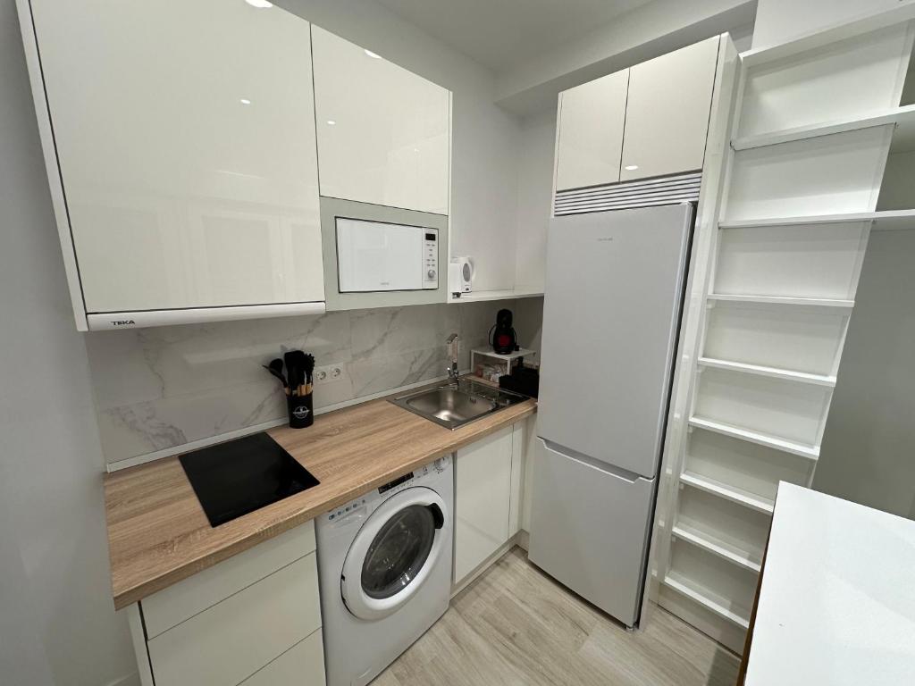 Una cocina con gabinetes blancos y lavadora. en Apartamento Andalucía 33 Izquierda, en Málaga