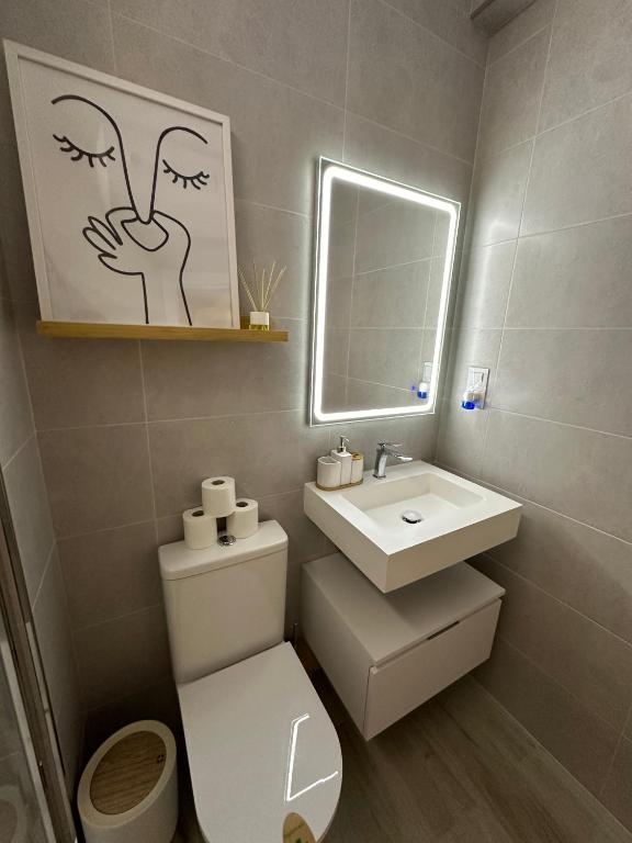 Un baño con inodoro, lavabo y espejo. en Apartamento Andalucía 33 Izquierda, en Málaga