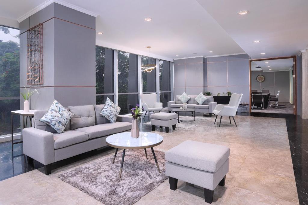a living room with a couch and tables and chairs at Somerset Kencana Jakarta in Jakarta