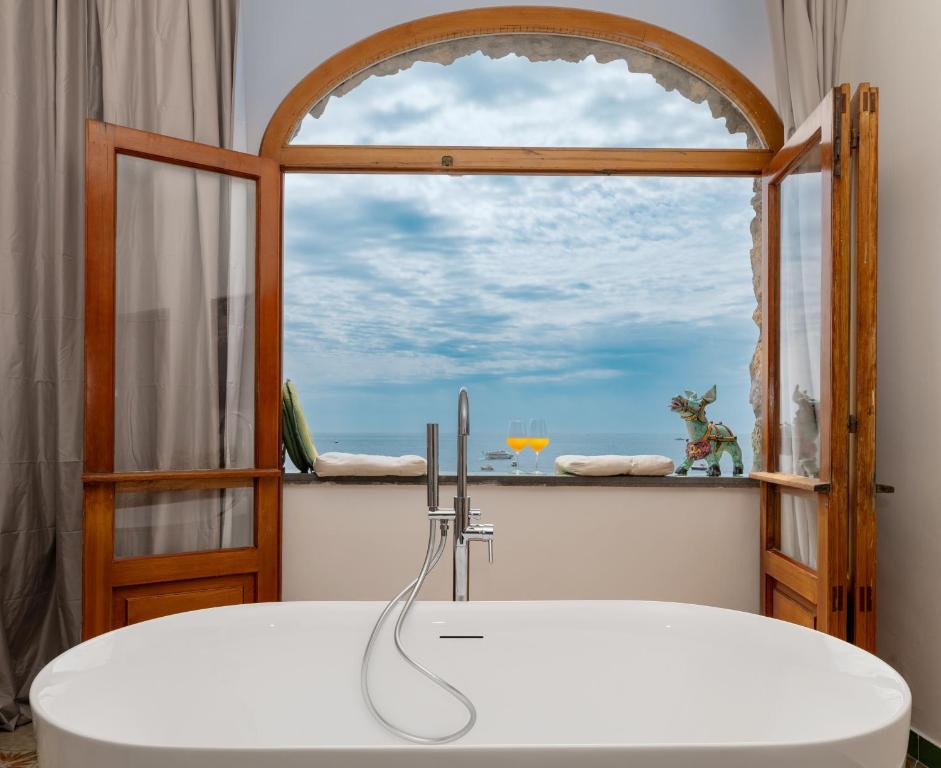 baño con bañera y ventana en La Dolce Vita a Positano boutique hotel, en Positano