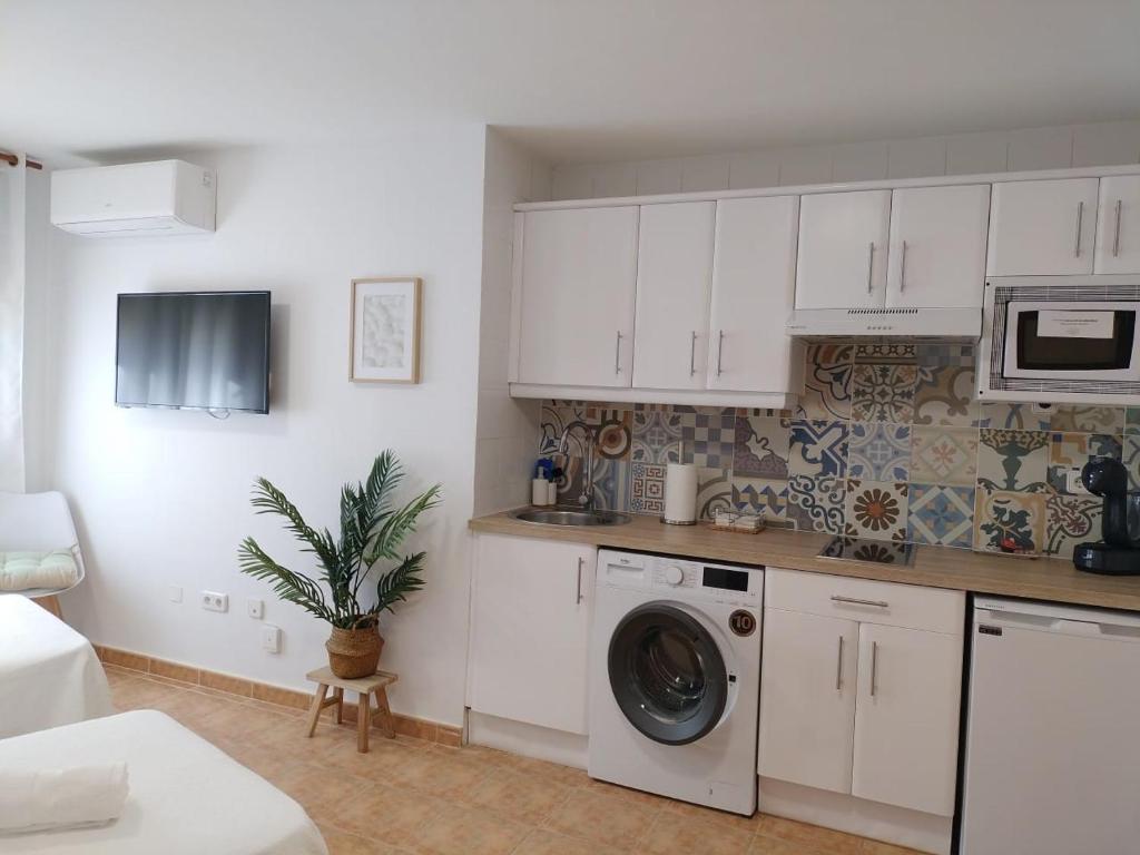 a kitchen with white cabinets and a washing machine at Estudios El Quijote in Alcalá de Henares
