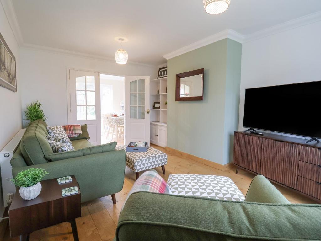 a living room with two couches and a flat screen tv at 23 Church Farm Lane in Halesworth