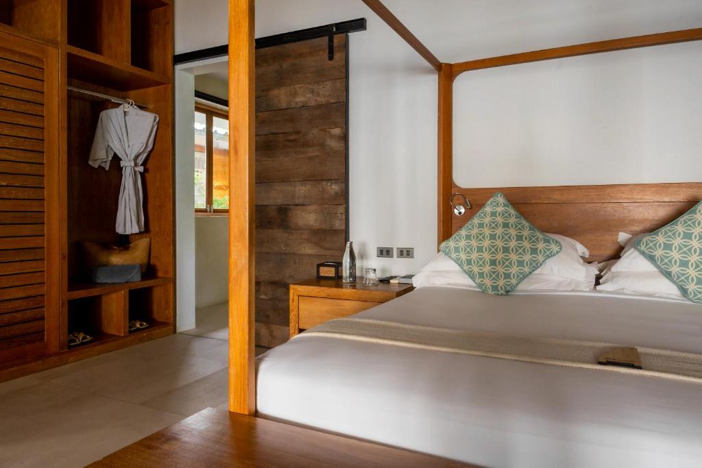una camera con un grande letto con testiera in legno di The Cove a Panwa Beach